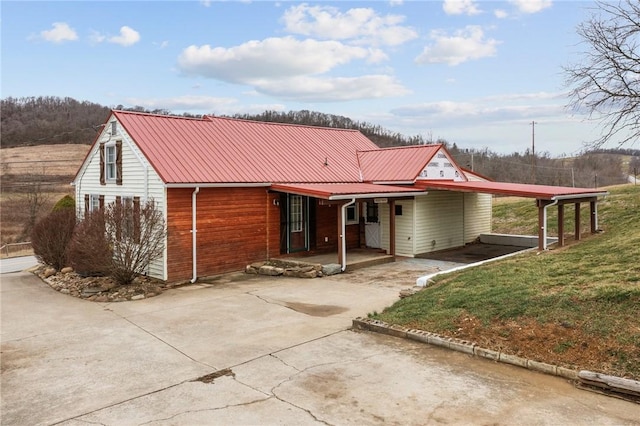 view of front of home featuring driveway, metal roof, a front lawn, and an attached carport