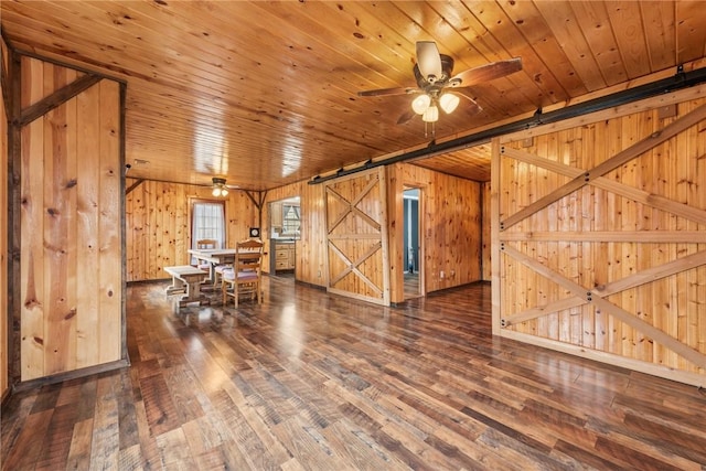 interior space with wood ceiling, wood finished floors, wooden walls, and a barn door