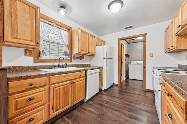 kitchen featuring white appliances, visible vents, dark countertops, washer / clothes dryer, and a sink