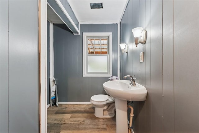 bathroom featuring baseboards, a sink, toilet, and wood finished floors