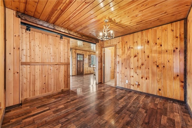 unfurnished room with a notable chandelier, a barn door, wood walls, wood finished floors, and wooden ceiling