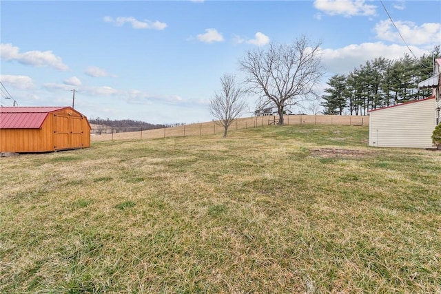 view of yard with an outbuilding, a rural view, fence, and a shed