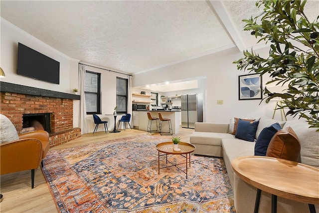 living room with light wood-style flooring, a brick fireplace, ornamental molding, and a textured ceiling