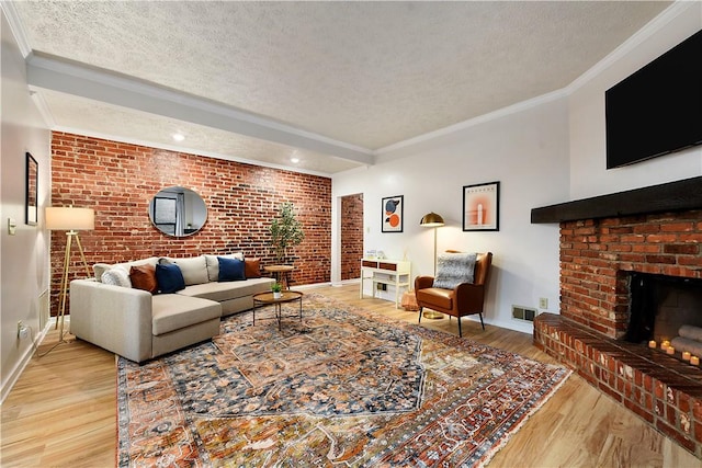 living room with ornamental molding, visible vents, a textured ceiling, and wood finished floors