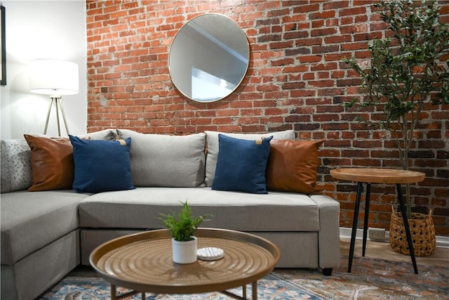 living room featuring brick wall and wood finished floors