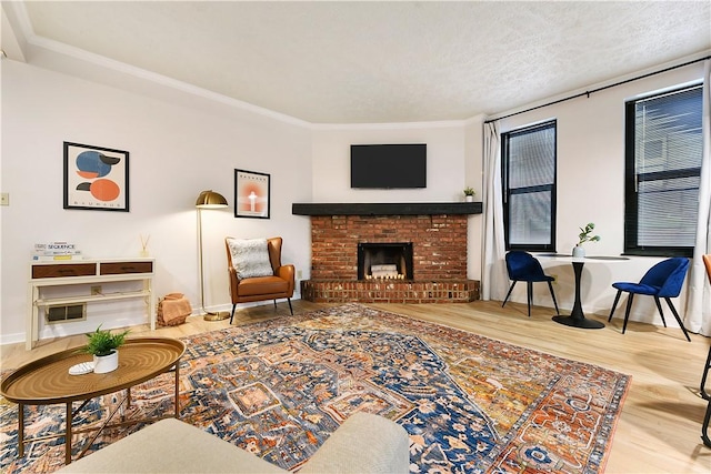 living room featuring a textured ceiling, ornamental molding, a fireplace, and wood finished floors