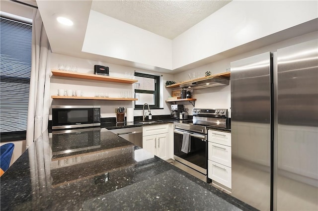 kitchen featuring a textured ceiling, under cabinet range hood, a sink, appliances with stainless steel finishes, and open shelves