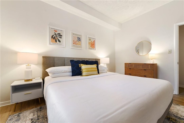 bedroom featuring a textured ceiling, wood finished floors, and baseboards