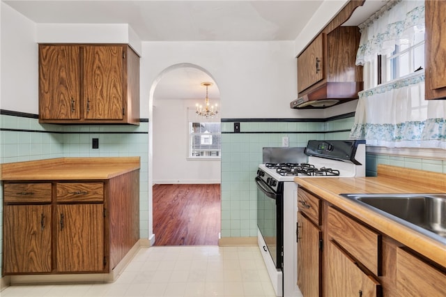 kitchen featuring a healthy amount of sunlight, white gas range oven, light countertops, and tile walls