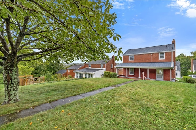 view of front facade featuring brick siding, a chimney, and a front lawn