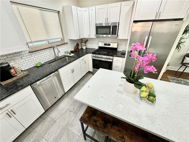 5620 Stanton Ave, East Liberty, PA 15206 - kitchen featuring tasteful backsplash, white cabinets, dark stone countertops, stainless steel appliances, and a sink