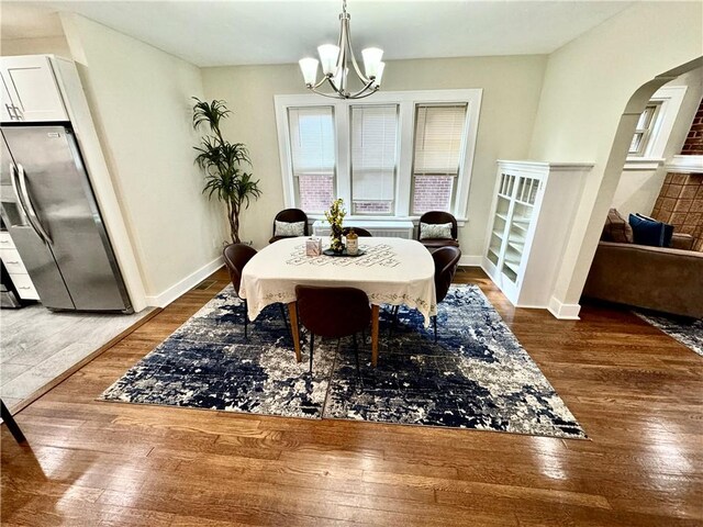 5620 Stanton Ave, East Liberty, PA 15206 - dining space with hardwood / wood-style flooring, baseboards, arched walkways, and an inviting chandelier