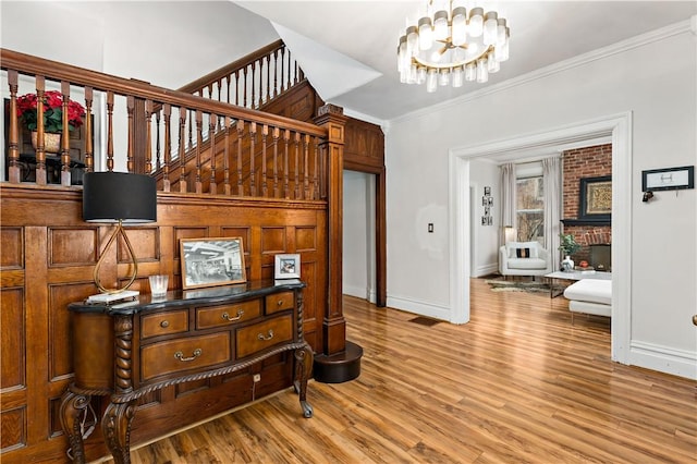 interior space with a fireplace, ornamental molding, a notable chandelier, and wood finished floors