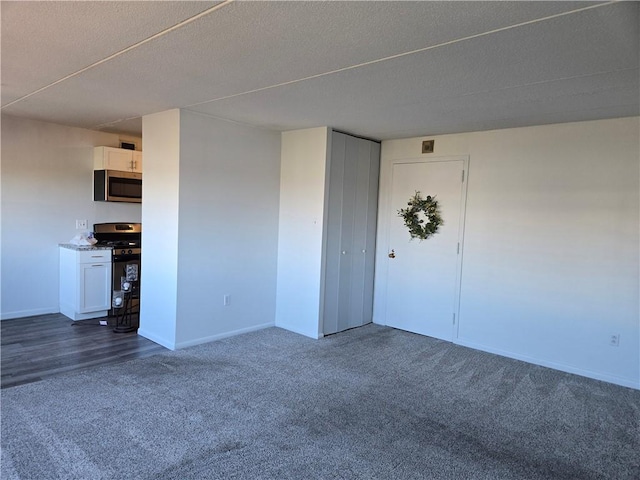 empty room with dark colored carpet, baseboards, and a textured ceiling