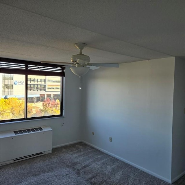 carpeted spare room featuring radiator, baseboards, and ceiling fan