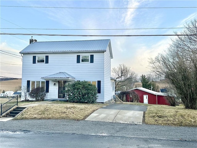 view of front of property featuring an outbuilding, metal roof, and a chimney