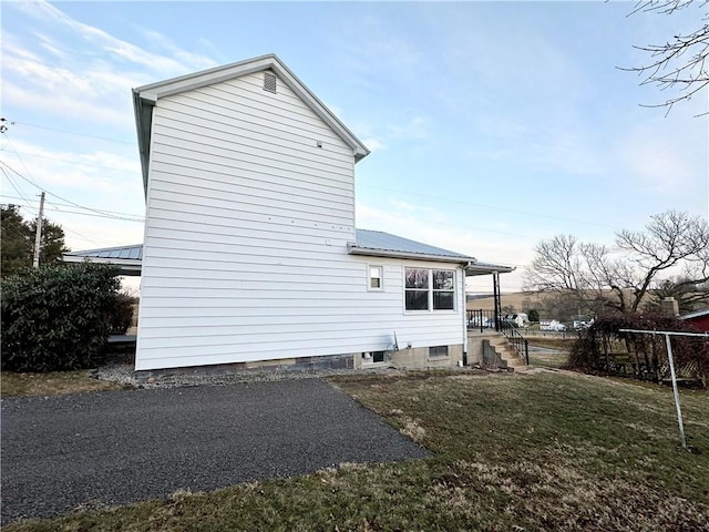 rear view of house with metal roof and a lawn