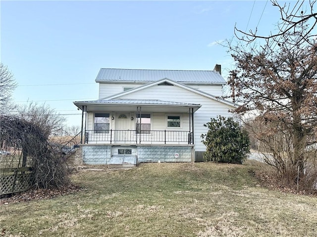 view of front of home featuring a front yard, covered porch, metal roof, and a chimney