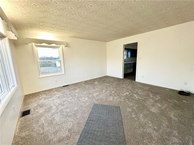 unfurnished room featuring visible vents, carpet flooring, and an ornate ceiling