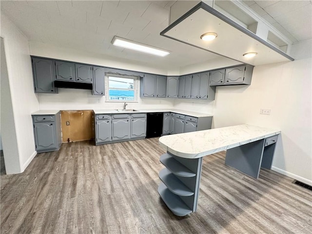 kitchen featuring open shelves, wood finished floors, a sink, and gray cabinetry