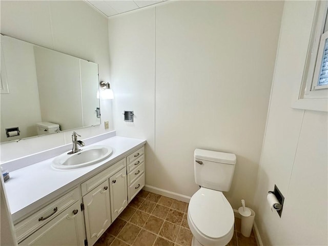 bathroom featuring baseboards, vanity, and toilet