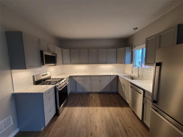 kitchen with tasteful backsplash, visible vents, dark wood-type flooring, stainless steel appliances, and a sink