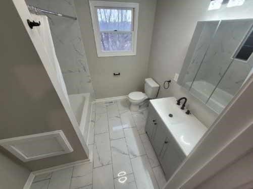 bathroom featuring toilet, shower / bath combo with shower curtain, vanity, and baseboards