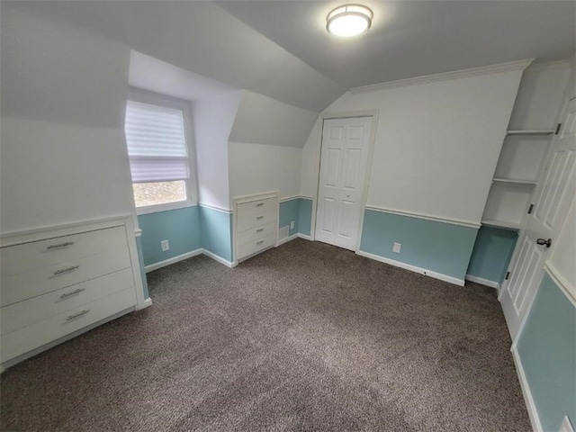 bonus room with lofted ceiling, dark colored carpet, and baseboards