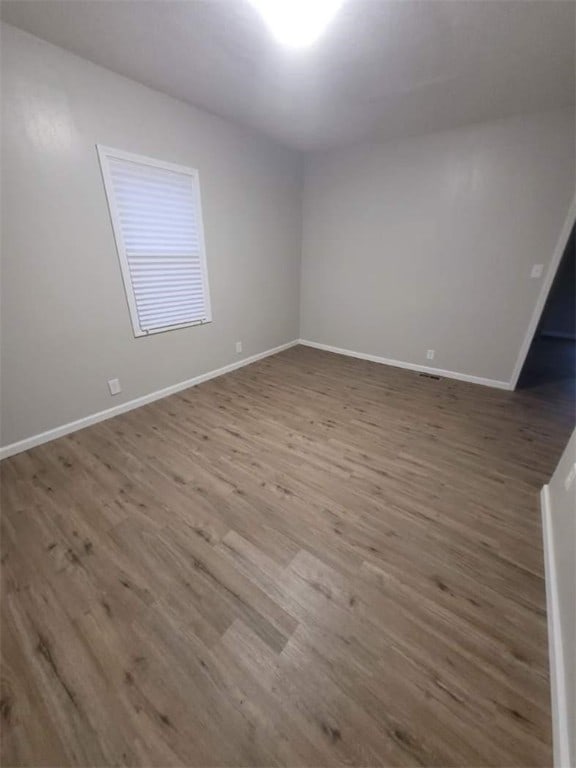 spare room featuring baseboards and wood finished floors