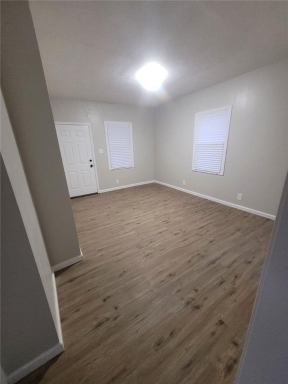 empty room with dark wood-type flooring and baseboards