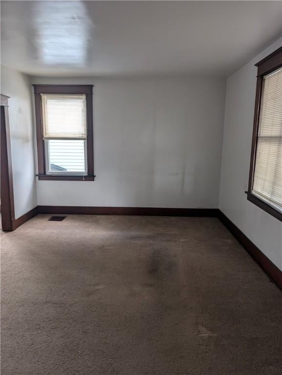 empty room featuring visible vents, baseboards, and carpet flooring