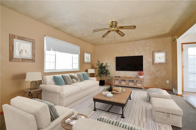 living room featuring visible vents, baseboards, and a ceiling fan