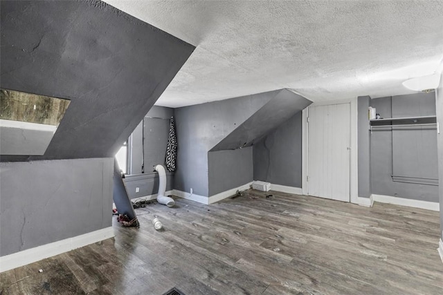 bonus room featuring lofted ceiling, a textured ceiling, baseboards, and wood finished floors