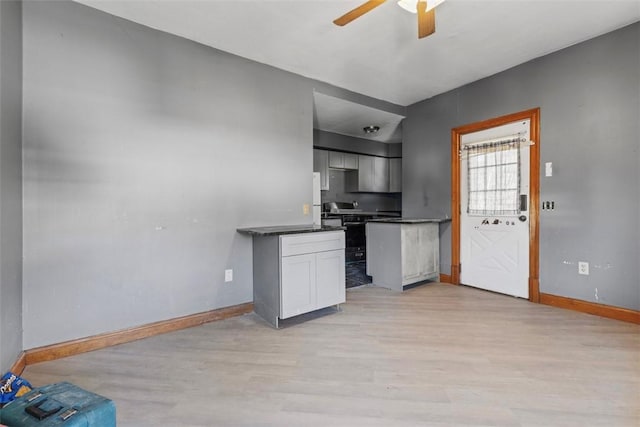 kitchen with light wood-type flooring, dark countertops, baseboards, and white cabinets