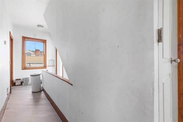 corridor featuring light wood-style flooring, baseboards, and an upstairs landing