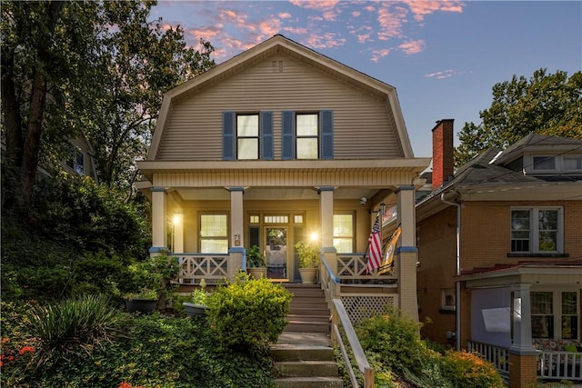 view of front of home with stairway, a porch, and a gambrel roof