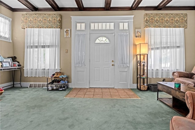 carpeted foyer featuring a healthy amount of sunlight, beamed ceiling, and visible vents