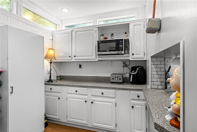 kitchen with a toaster, open shelves, light countertops, and white cabinets