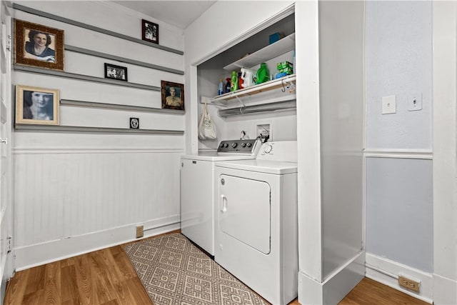 clothes washing area with laundry area, washing machine and clothes dryer, and wood finished floors