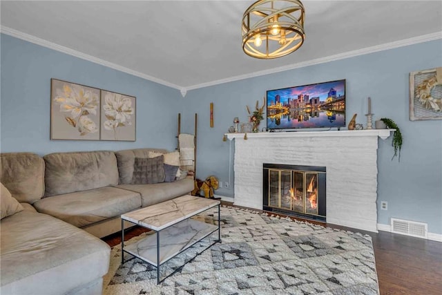 living room featuring wood finished floors, visible vents, baseboards, a glass covered fireplace, and crown molding