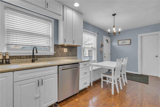 kitchen featuring tasteful backsplash, wood-type flooring, white cabinets, a sink, and dishwasher