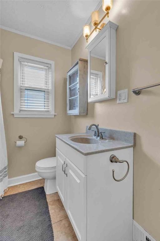 bathroom with toilet, vanity, baseboards, tile patterned floors, and crown molding