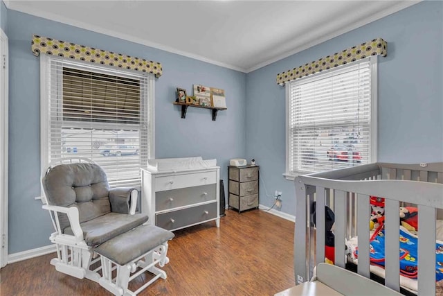 bedroom featuring ornamental molding, a crib, baseboards, and wood finished floors