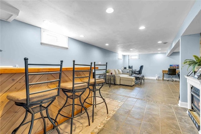 bar with baseboards, a healthy amount of sunlight, a glass covered fireplace, and recessed lighting