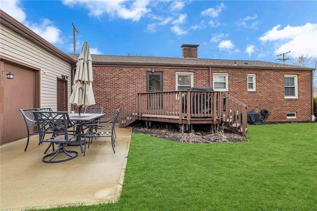 back of property with brick siding, a chimney, a lawn, a patio area, and a wooden deck