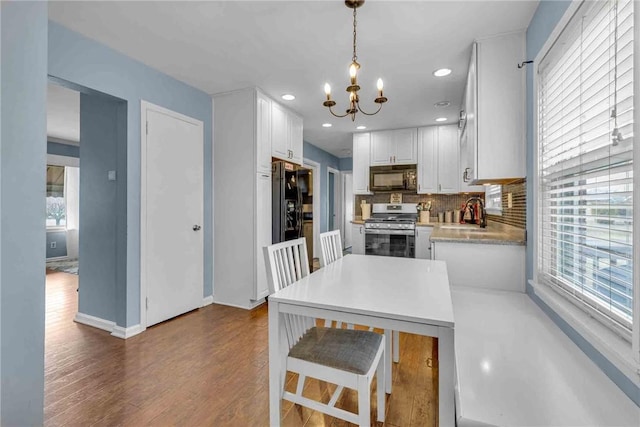 kitchen featuring tasteful backsplash, dark wood finished floors, light countertops, black appliances, and white cabinetry