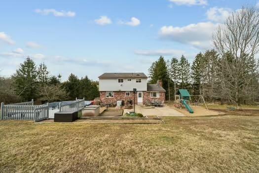 back of house featuring a patio area, a yard, a playground, and fence