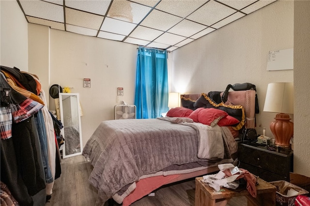 bedroom with a drop ceiling and wood finished floors