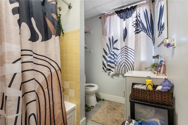 full bathroom with baseboards, toilet, shower / tub combo with curtain, vanity, and a paneled ceiling