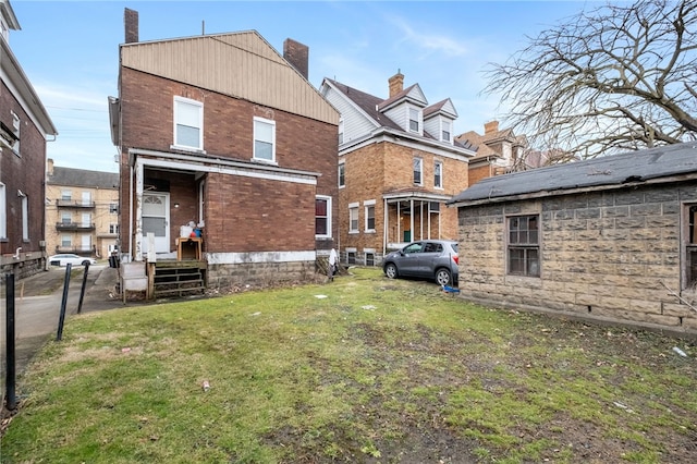 rear view of property with brick siding and a lawn